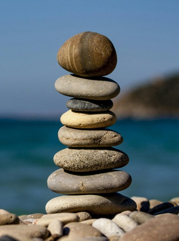 A stack of balanced stones on a beach with a tranquil ocean backdrop for meditation and zen.